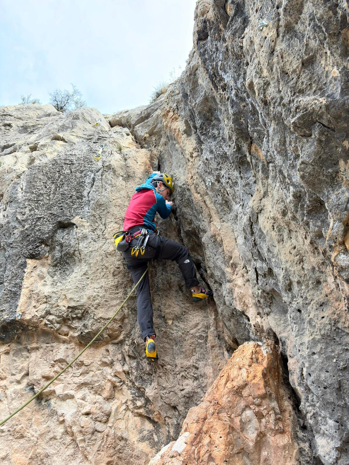 Escalador asegurado progresando por una vía de roca durante una clase de técnica de escalada