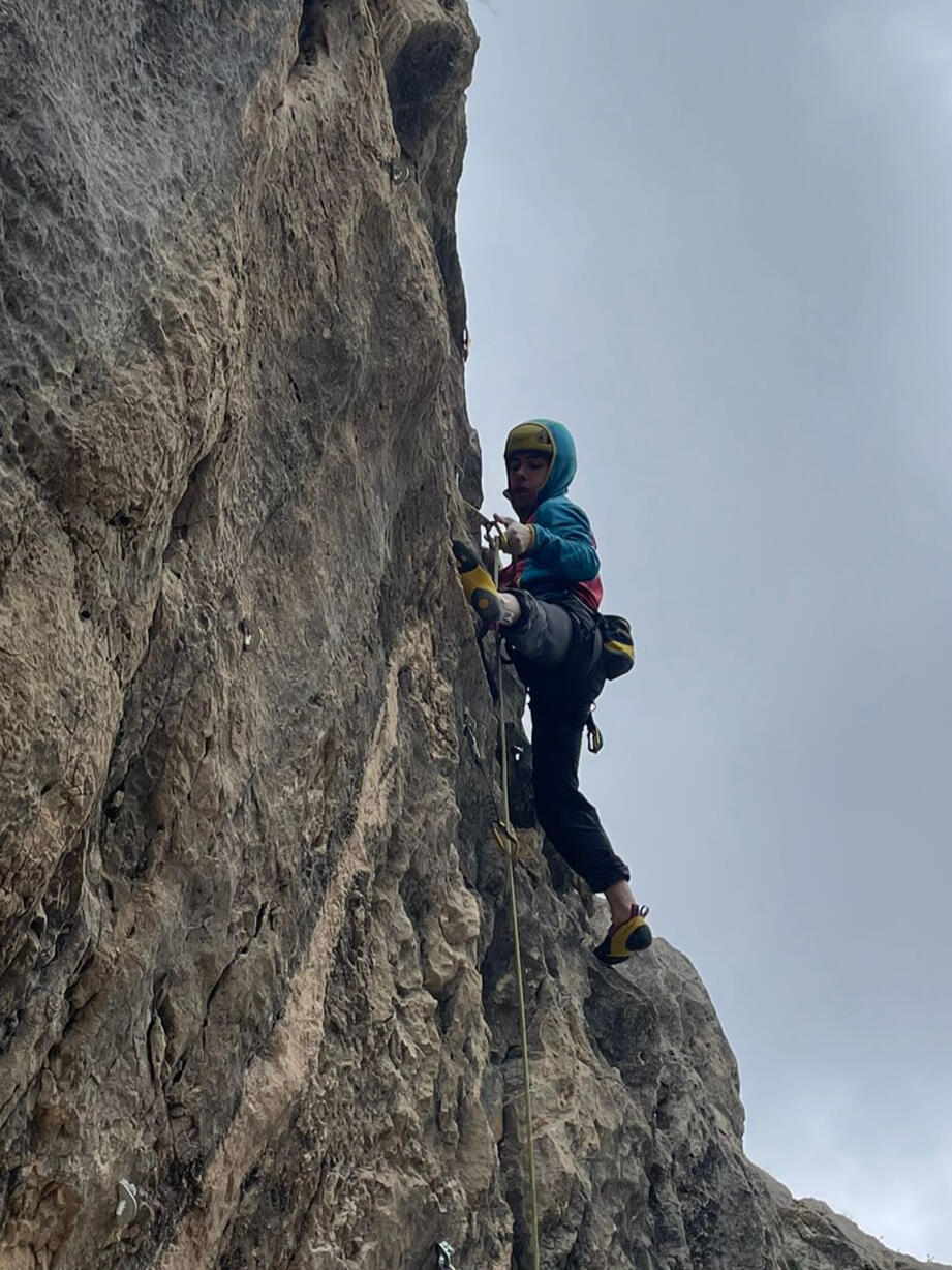 Escalador con casco chapando en una vía de roca para practicar seguridad y progresión